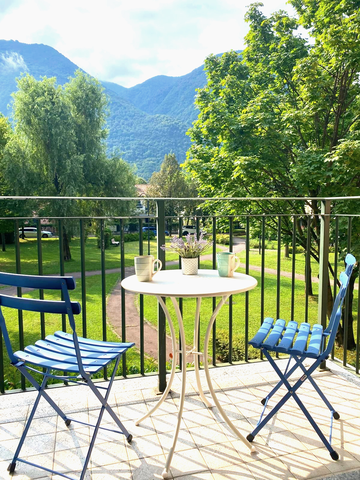 Tweede balkon met blauwe bistrotafel en bergzicht