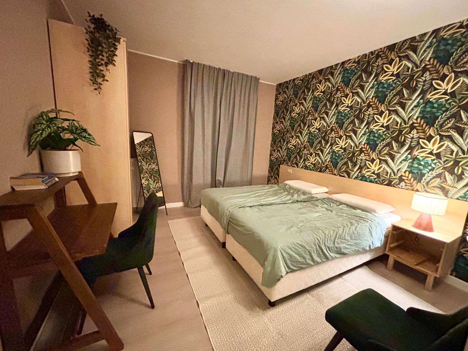 Slaapkamer 1 met tweepersoonsbed en tropisch behang