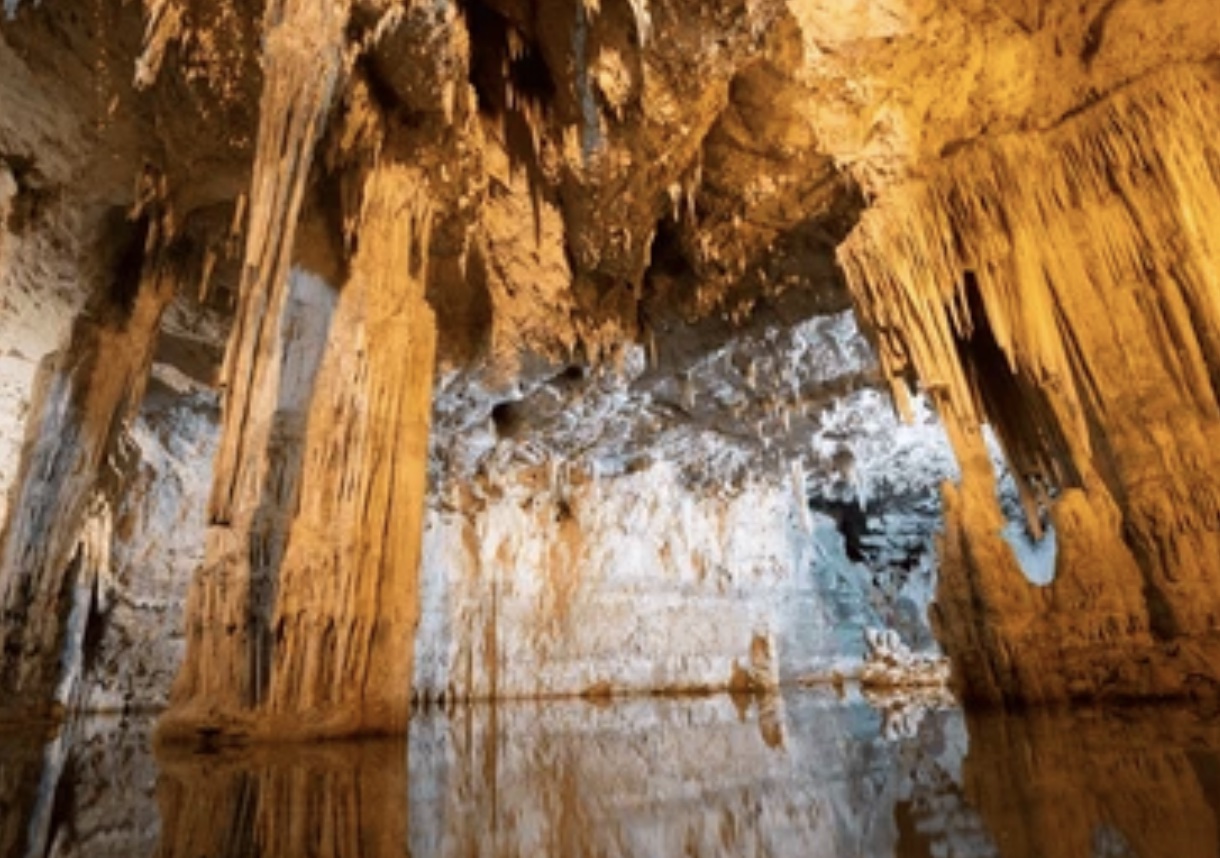 Grotten van Rescia met stalactieten en reflecties in ondergronds water